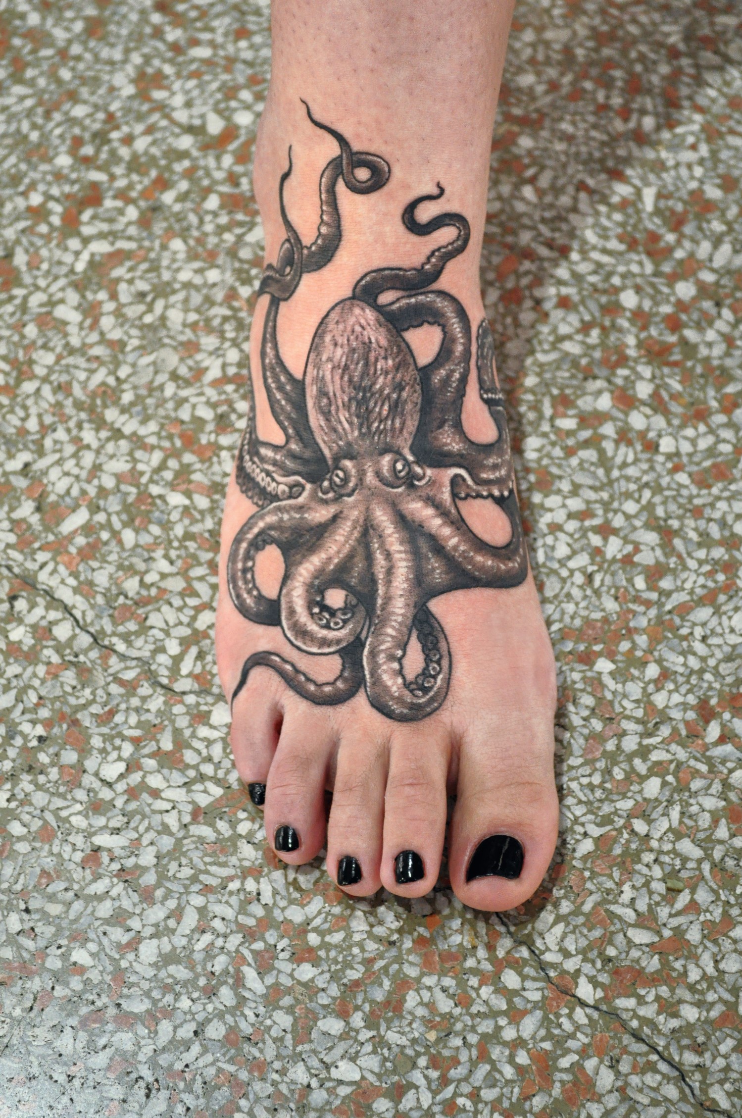 Tatouage de poulpe réaliste sur le pied.
